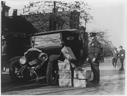 A policeman during the prohibition era, confiscating a wrecked automobile containing illegal liquors. [Courtesy]